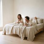 Couple with coffee in a linen dressed bed