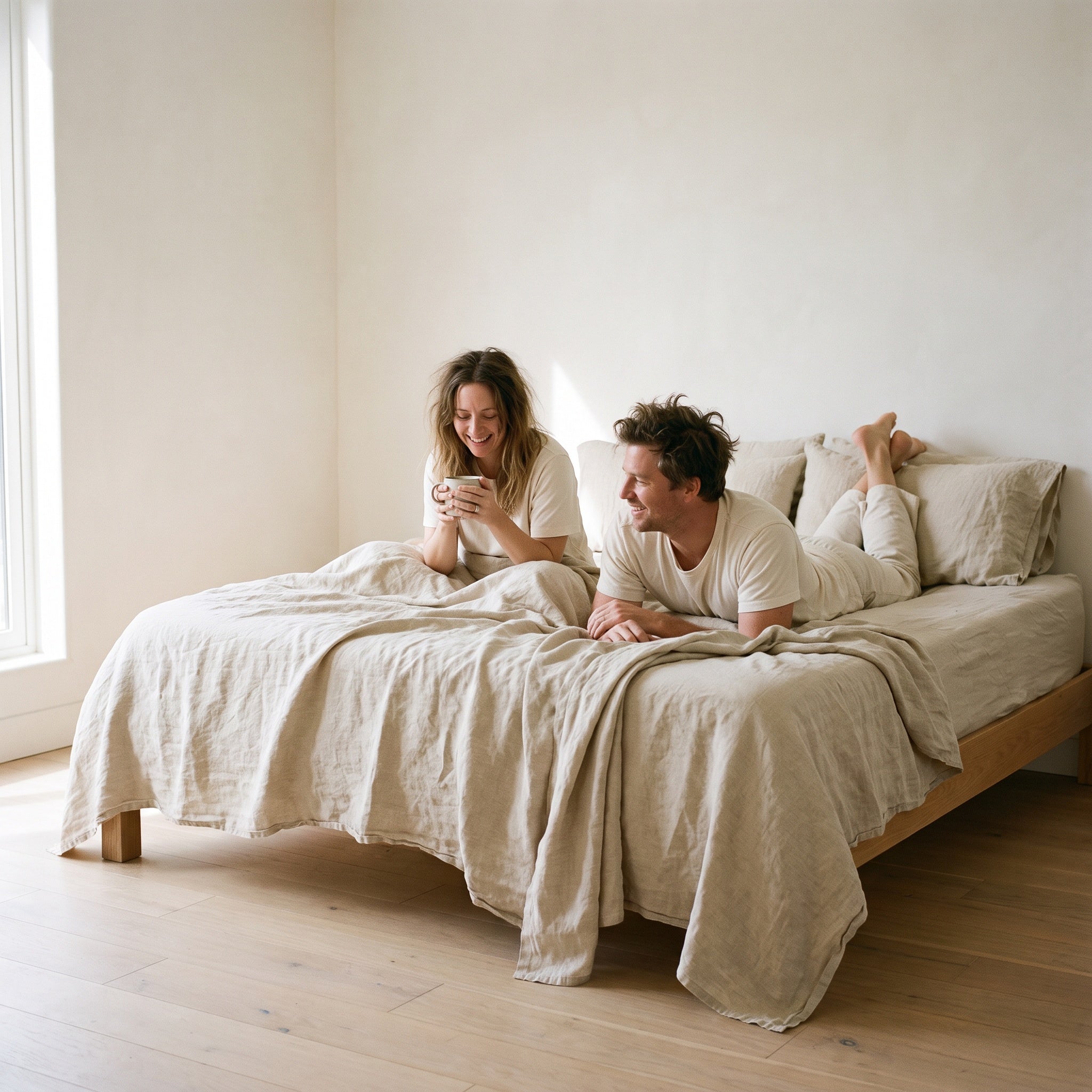 Couple with coffee in a linen dressed bed