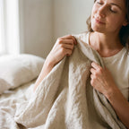 Woman pulling a washed linen sheet over the bed